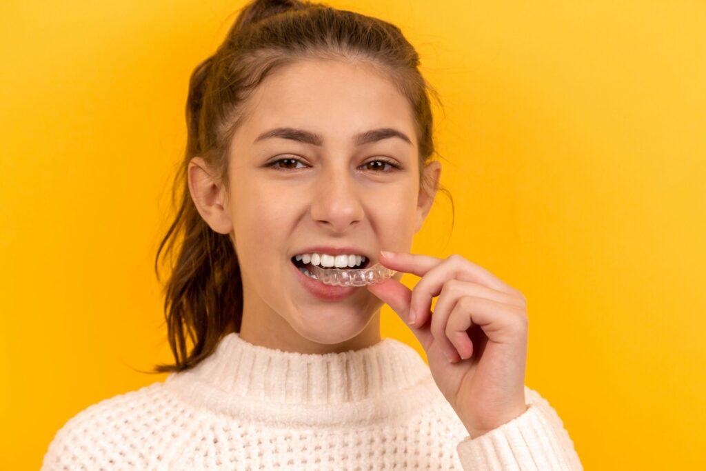 Choosing a dentist in Brentwood. Image of a young lady putting in an Invisalign retainer.